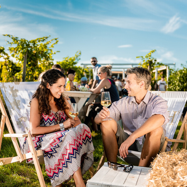 Ein Paar genießt im Weingarten ein Glas Weißwein